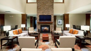 A hotel lobby with a fireplace, sofas, armchairs, and a patterned carpet.