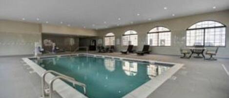 An indoor swimming pool with a clear view of the pool area, a bench, and a window.
