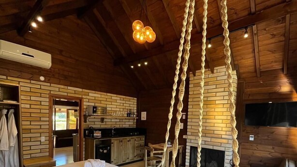 Una habitación acogedora con una cama grande, una hamaca colgante, chimenea y una zona de cocina.
