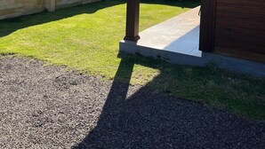 Una construcción de madera con techo de tejas, pared de piedra y un patio cubierto de césped.