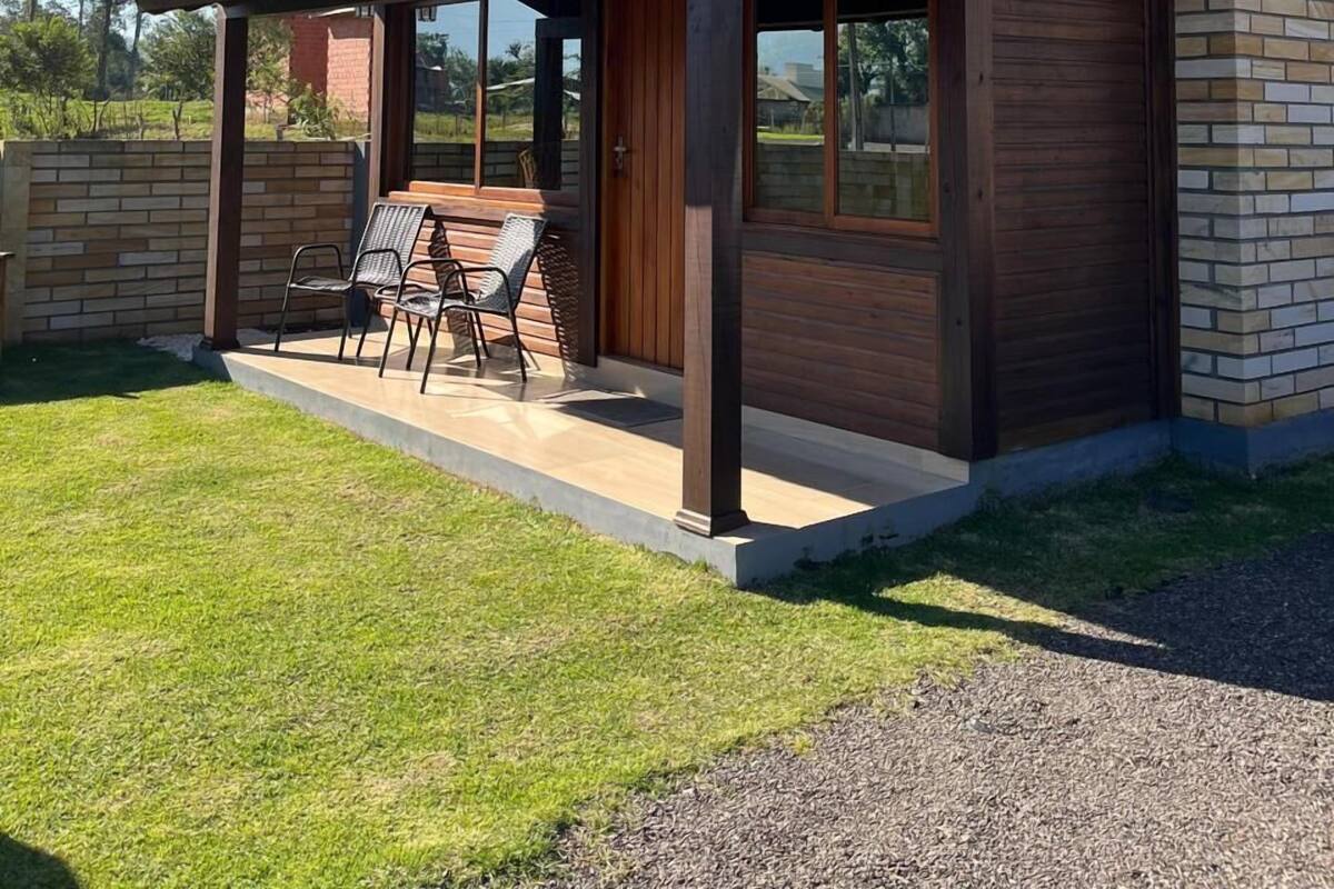 Une maison moderne dotée d’un patio couvert, de grandes fenêtres et d’une cheminée en briques.