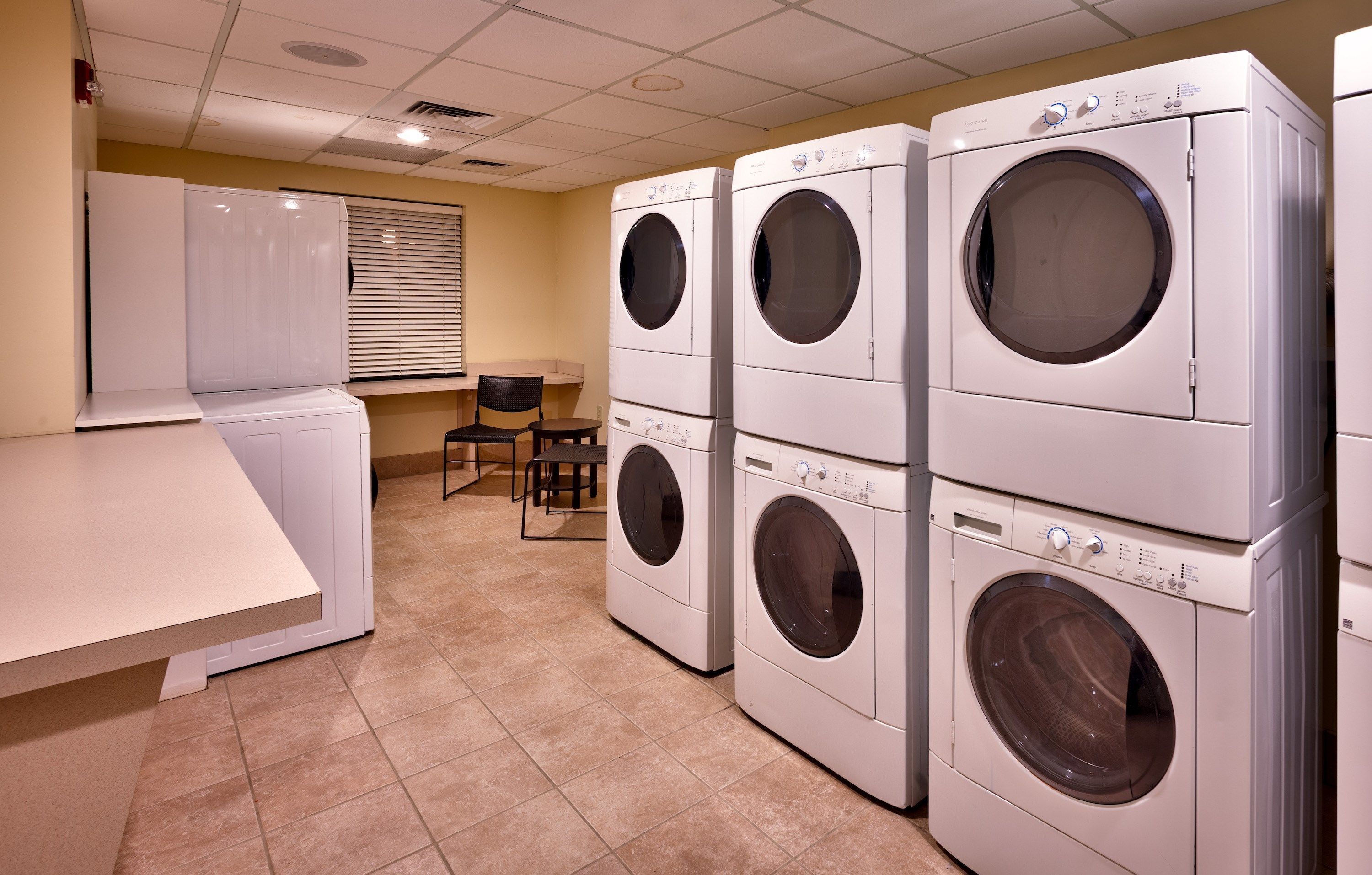 A laundry room with four stacked front-loading washing machines and a single dryer.