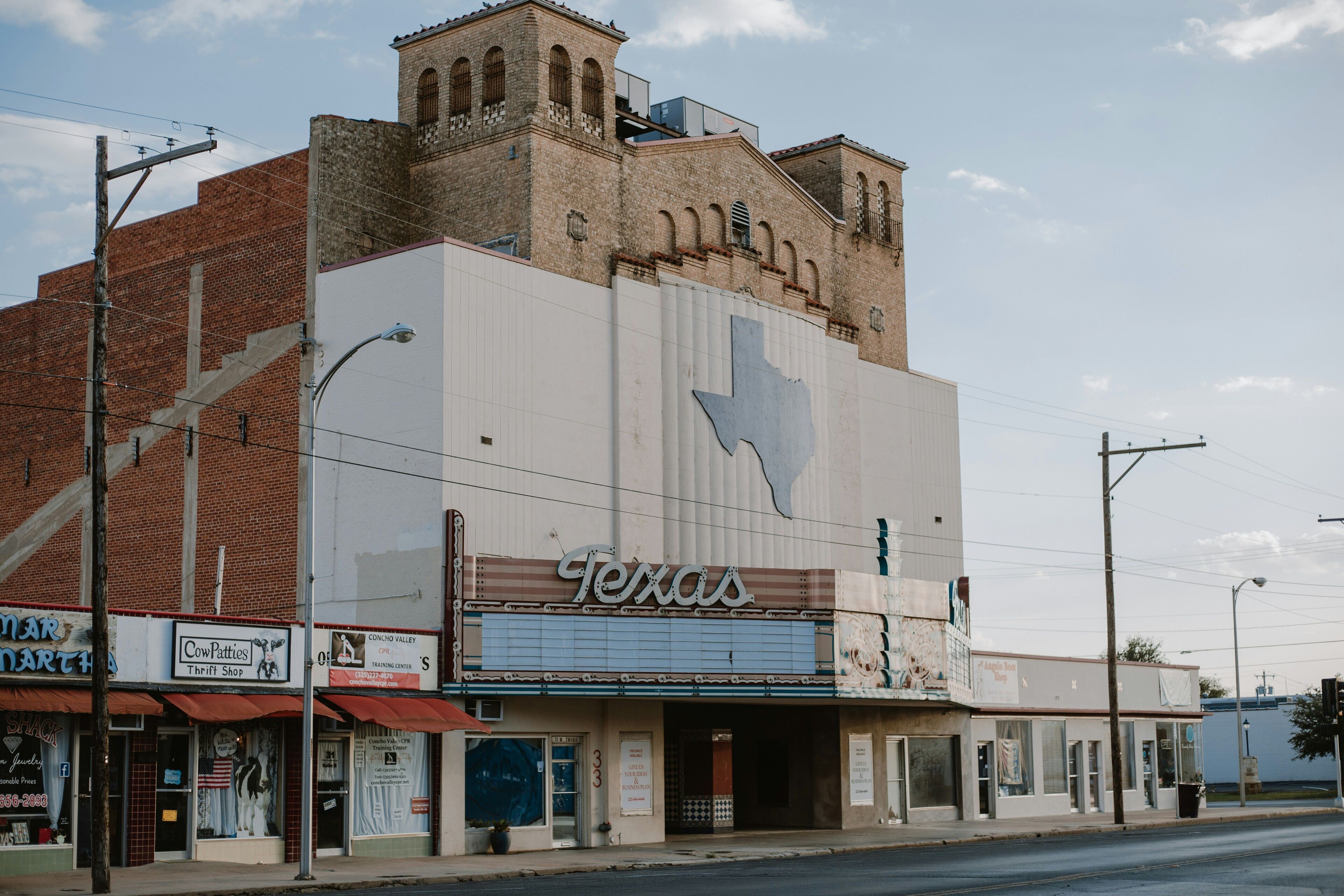 Un théâtre dont la façade est ornée du contour de l’État du Texas, une boutique de seconde main appelée « Cow Patties » et une station-service « Conoco Valley ».