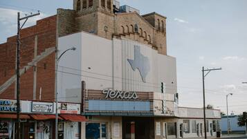 Un théâtre dont la façade est ornée du contour de l’État du Texas, une boutique de seconde main appelée « Cow Patties » et une station-service « Conoco Valley ».