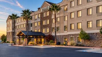 A multi-story hotel with a stone facade, a covered entrance, and a sign indicating 'Staybridge Suites.'