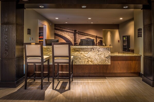 A kitchen with a granite countertop, two bar stools, and a built-in oven.