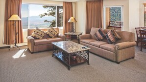 A living room with two sofas, a coffee table, and a view of mountains through large windows. - Access to Pools, Spa + Fitness Centre! (Stateline)