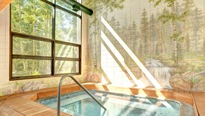 Un bain à remous doté d’une terrasse en bois, d’une fenêtre et d’une fresque représentant un paysage forestier.