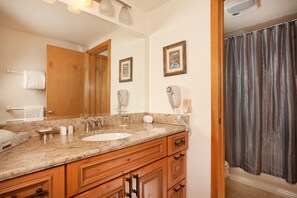 A bathroom with a wooden vanity, a large mirror, a sink, and a shower curtain. - Condo Along Snake River | Hot Tub Access | Shuttle (Keystone)