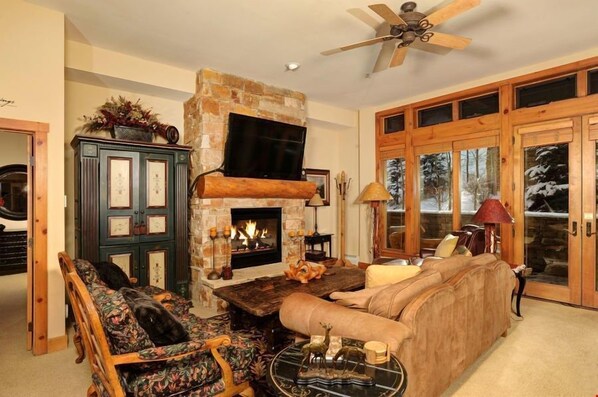 A cozy living room with a fireplace, a sofa, a coffee table, and a television.