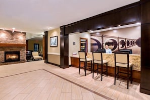 A hotel lobby with a reception desk, chairs, a fireplace, and a large wall mural.
