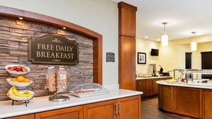 A breakfast area with a stone wall, a sign for free daily breakfast, and various food items on display. - Short Drive to Texas A&M | Outdoor Pool + Business Center + Fitness Center (College Station)