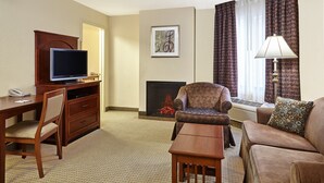 Habitación de hotel con televisión de pantalla plana, chimenea, sofá, escritorio y lámpara.