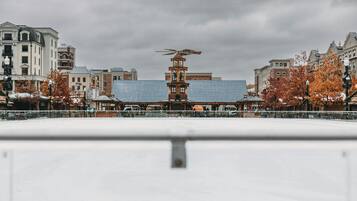 A snow-covered plaza with a central building featuring a clock tower and a distinctive roof ornament.