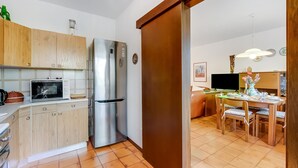 A modern kitchen with wooden cabinets, a stainless steel refrigerator, and a microwave. - Dora - Riva del Garda Apartment With Terrace (Riva del Garda)