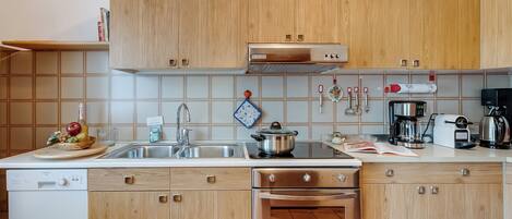 A modern kitchen with wooden cabinets, stainless steel appliances, and a built-in oven.