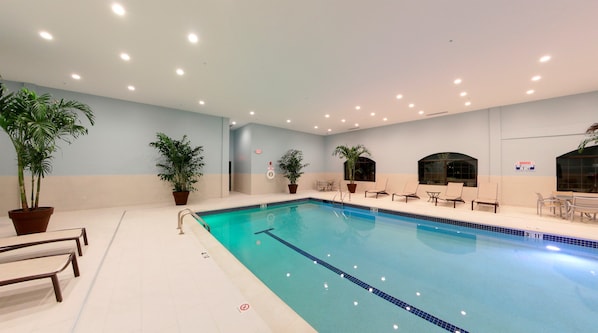 A swimming pool with lounge chairs and potted plants.
