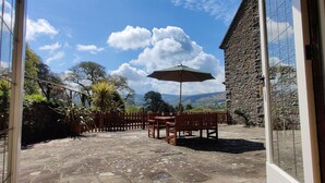 A patio with stone flooring, wooden furniture, and a table with an umbrella. - bossington bunkhouse (Bossington)