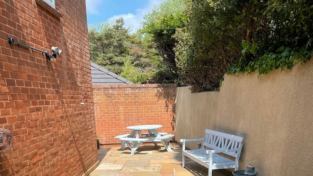 A patio with stone flooring, a white bench, and a picnic table. - Seaside Retreat in Exmouth With Stunning Views (Exmouth)