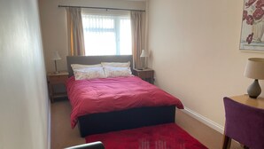 A bedroom with a bed, a chair, a desk, and a window with curtains. - Seaside Retreat in Exmouth With Stunning Views (Exmouth)