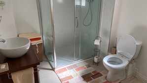 A bathroom with a glass-enclosed shower, a white sink, a toilet, and a small wicker basket. - Seaside Retreat in Exmouth With Stunning Views (Exmouth)