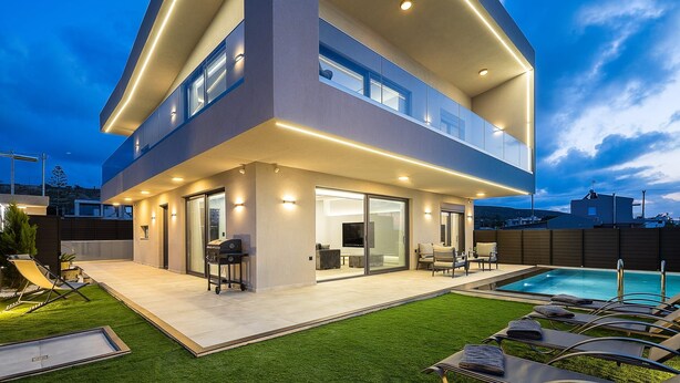 A modern two-story house with a covered patio, a swimming pool, and a well-maintained lawn.