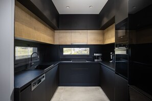 A modern kitchen with dark cabinetry, a window, and built-in appliances. - Resmi SeaView Villa, Villa (Kokkini Hani)