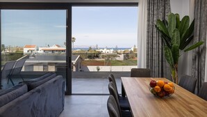A modern living room with a large sliding glass door leading to a balcony with a city view.