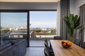 A modern living room with a large sliding glass door leading to a balcony with a city view.