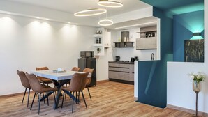 A modern kitchen with a dining area, featuring a wooden floor, a central island, and pendant lighting. - Regarda - Emerald apartment near the beach with pool (Bardolino)
