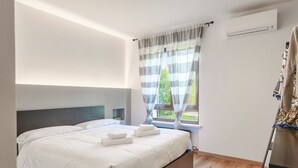 A modern bedroom with a large bed, a window with curtains, and a wooden floor. - Regarda - Emerald apartment near the beach with pool (Bardolino)