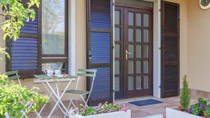 A patio with a table and chairs, a door with a window, and potted plants. - Regarda - Emerald apartment near the beach with pool (Bardolino)