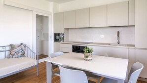 A compact kitchen with white cabinets, a dining table, and chairs. - Regarda - Lagobaldo Apartment with pool and garden (Lazise)