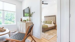 A modern bedroom with a bed, bedside table, and a large window. - The Lyric Loft - Walkable & Close to Downtown (Nashville)