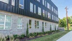 A modern building with a dark facade, multiple windows, and a well-maintained lawn. - The Lyric Loft - Walkable & Close to Downtown (Nashville)