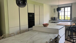 A modern kitchen with a marble countertop, a built-in oven, and a dining area with a table and chairs. - Pretty villa in the forest of Le Touquet Ideal family vacation ❤️classé 4*! (le touquet)
