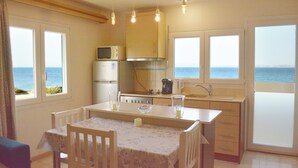 A kitchen with a view of the sea, a dining table, chairs, and a microwave. - Aegean Bliss Residences Karfas (Chios)