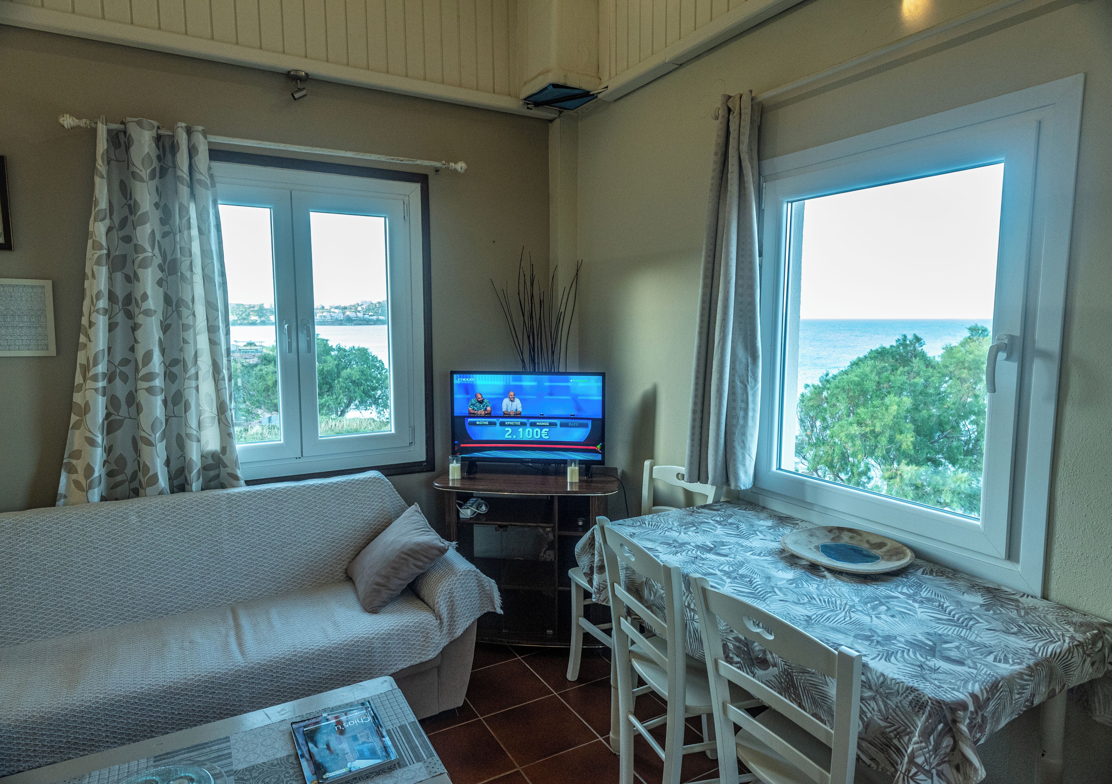Une chambre avec un lit, une télévision, une table et une vue sur la mer.