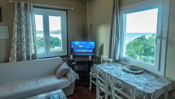 Une chambre avec un lit, une télévision, une table et une vue sur la mer.