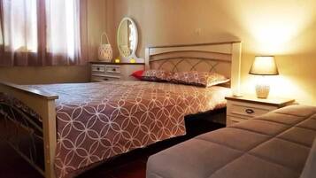 Quarto com cama, mesas de cabeceira, espelho e janela com cortinas.