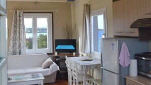 A compact kitchen with a dining area, a sofa, and a table with chairs. - Aegean Bliss Residences Karfas (Chios)