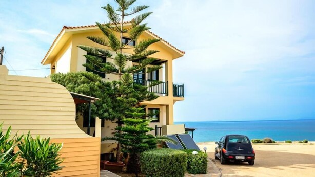 A two-story building with a balcony, a car parked in front, and a view of the sea. - Aegean Bliss Residences Karfas (Chios)