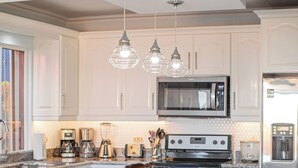 A modern kitchen with white cabinetry, a large island with stools, stainless steel appliances, and pendant lighting. - Villa Cielo — 3BR Oceanview Pool, Ocotal CR (Ocotal)