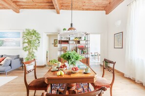 A dining area with a wooden table, chairs, a hanging light fixture, and a bookshelf filled with books and plants. - Lunav House in Lucca (Lucca)