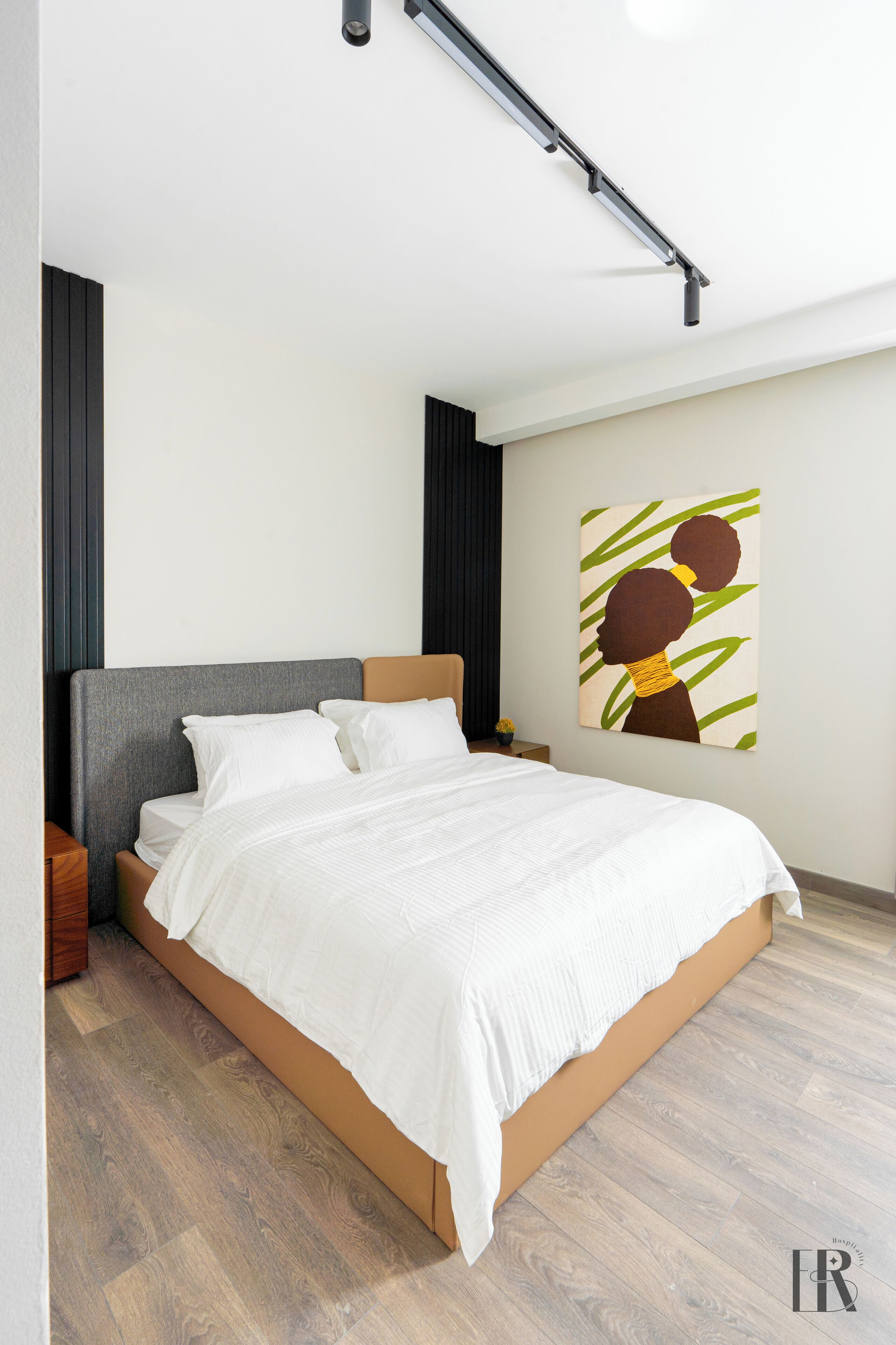 Ein modernes Schlafzimmer mit einem Bett, einem hölzernen Kopfteil und einem Bild an der Wand.