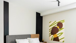 A modern bedroom with a bed, wooden headboard, and a painting on the wall. - Apartment in El Sheikh Zayed (Giza Governorate)