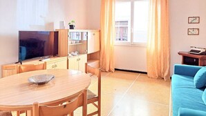 Un salon avec un téléviseur, un meuble en bois, un canapé bleu et une table à manger.