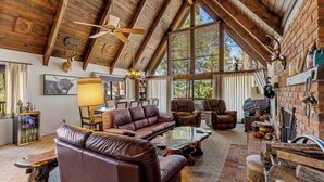 A rustic interior with a high ceiling, leather sofas, a coffee table, and a fireplace.