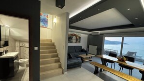 A modern interior with a staircase leading to a balcony with a view of the sea.