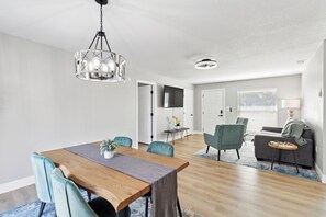 Um espaço de estar moderno com área de jantar, sofá e televisão na parede.